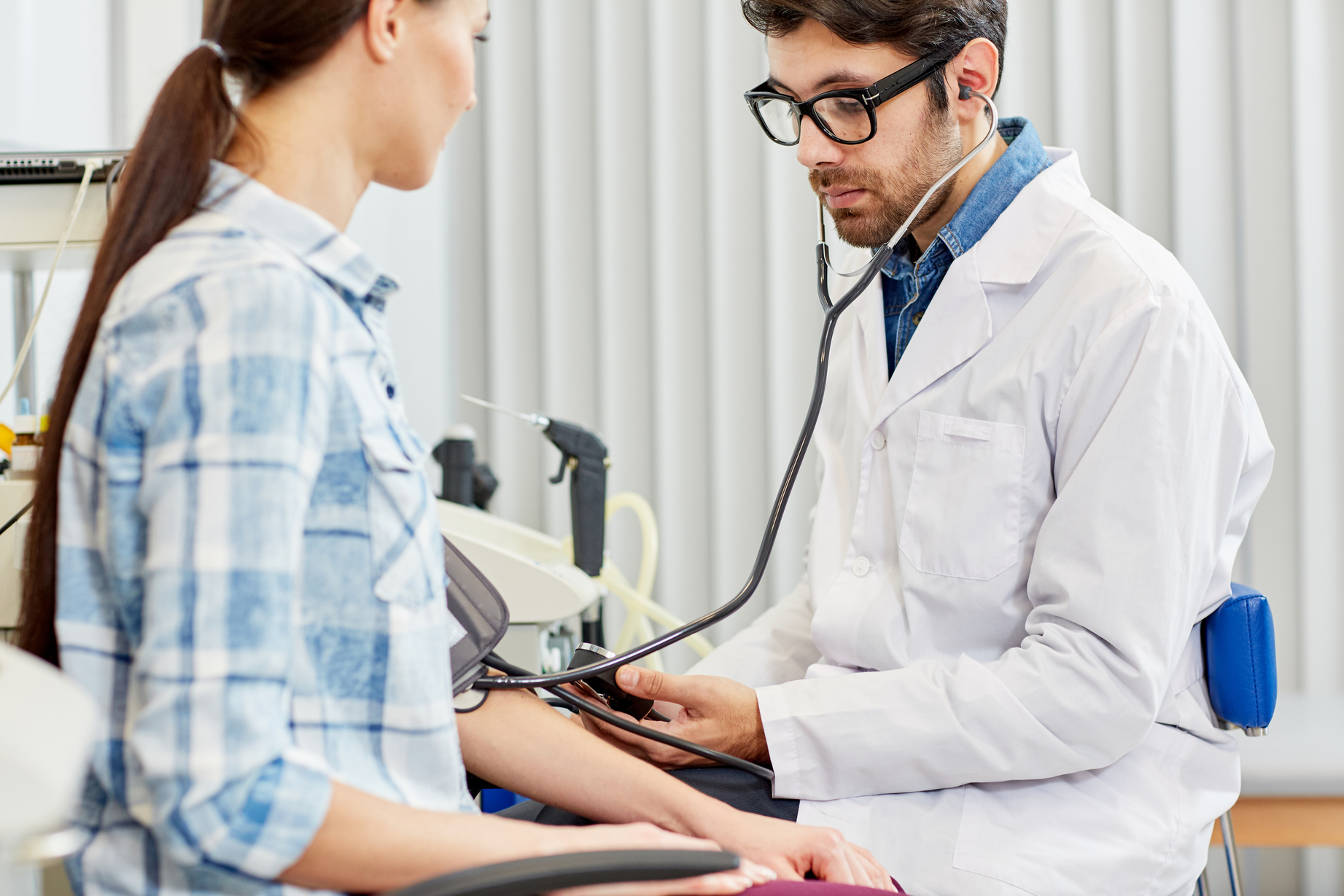 Contemporary therapeutist measuring blood pressure of his patient in clinics