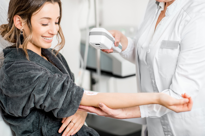 Senior doctor finding veins with vein scanner device to a young patient in a medical resort