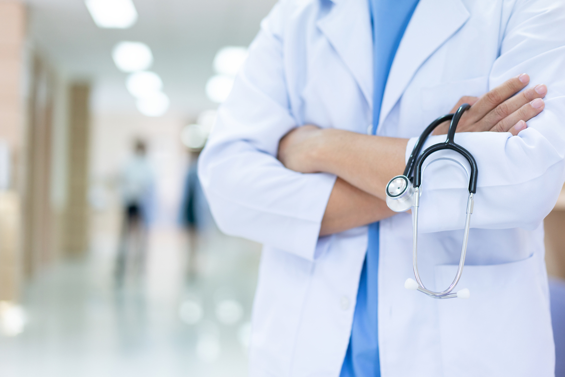 Doctor in arms crossed with stethoscope standing at hospital corridor. healthcare insurance and medical concept