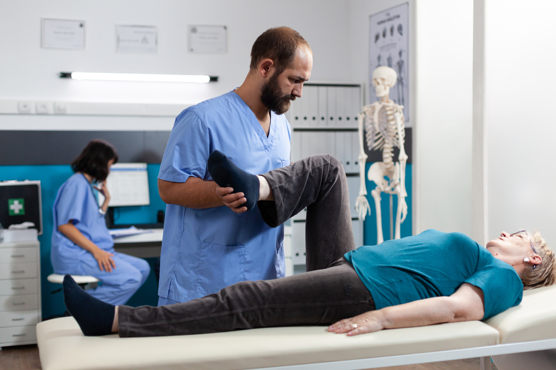 General practitioner helping retired woman with joint pain for orthopedic examination. Physician doing chiropractic exercise for elder patient with leg and knee injury, treating arthritis.