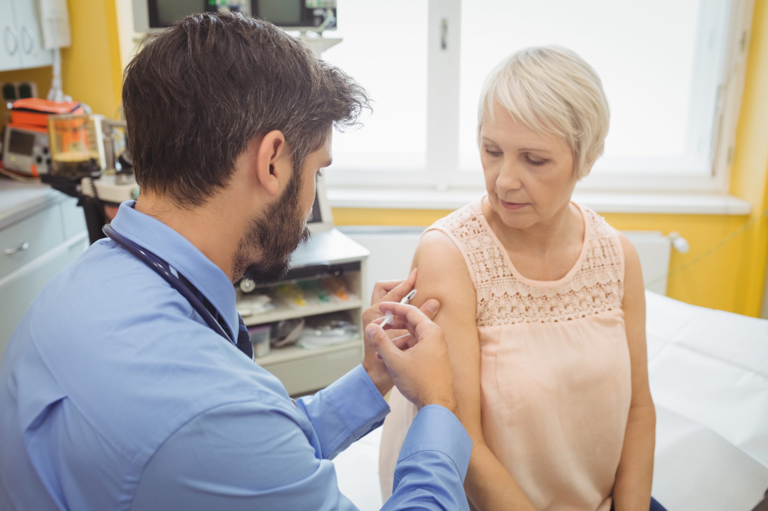 Male doctor giving an injection to a patient at the hospital