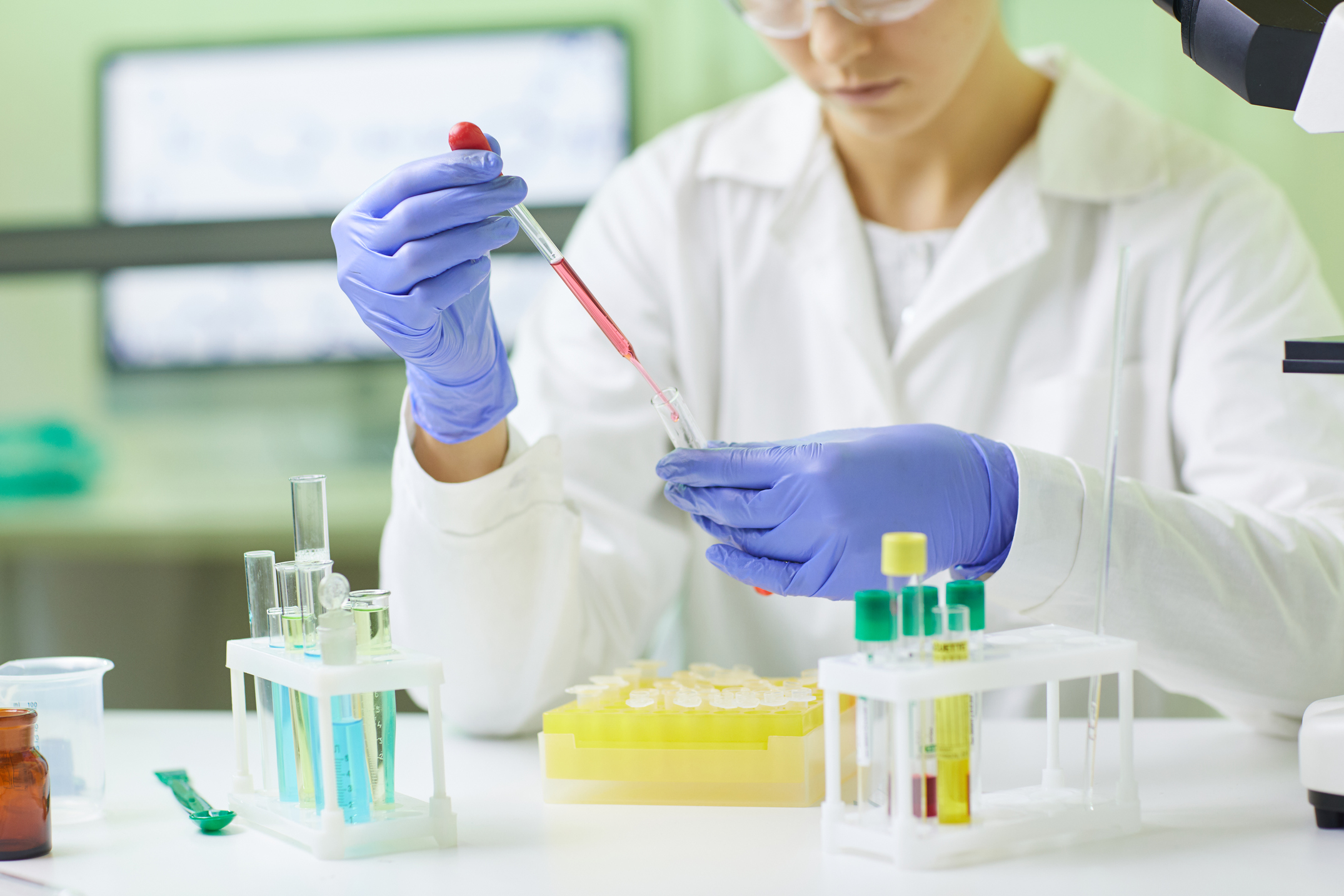 Closeup of young female scientist preparing blood test sample using dropper while working in medical laboratory, copy space